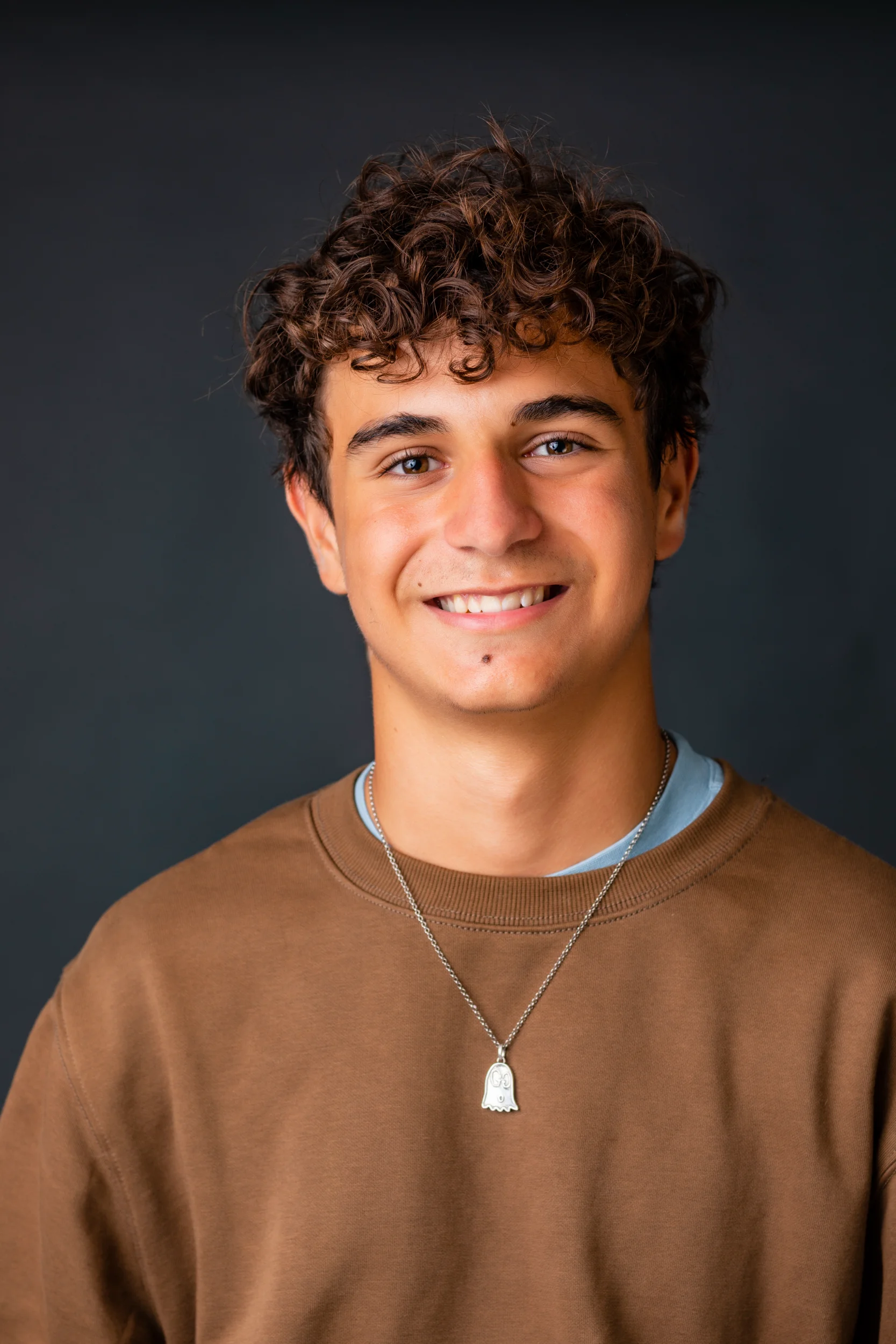 Ung mand med smil og naturlige krøller i portræt