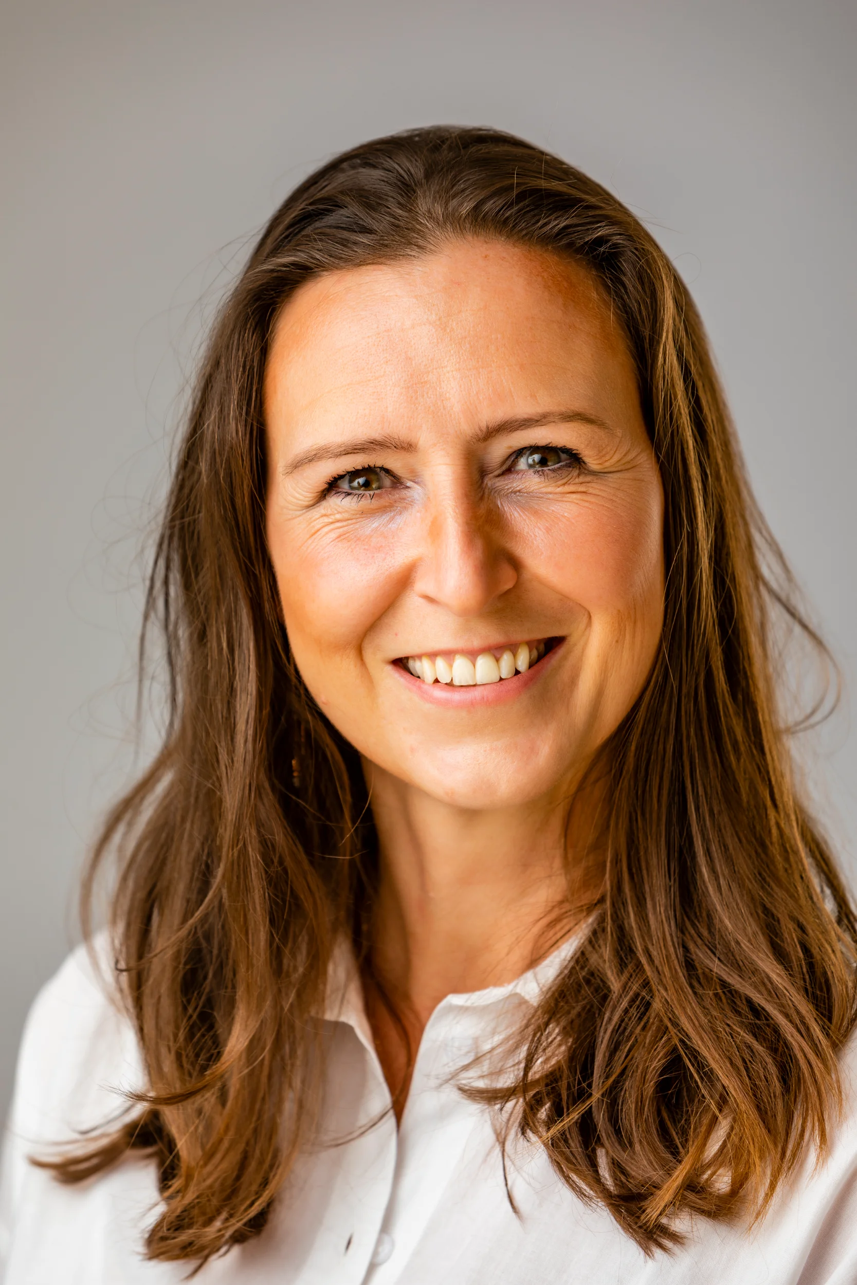 Sort-hvidt portrætfoto af smilende kvinde med langt, mørkt hår og detaljerede ansigtsudtryk i naturligt lys.