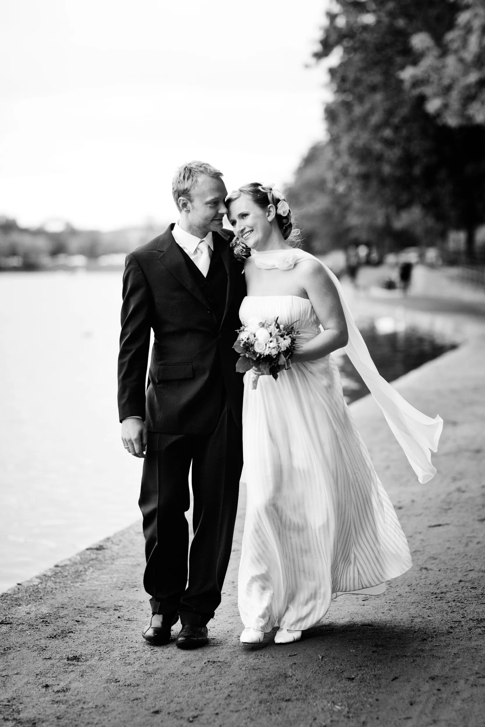 Bryllupspar slentrer langs vandet i naturligt lys