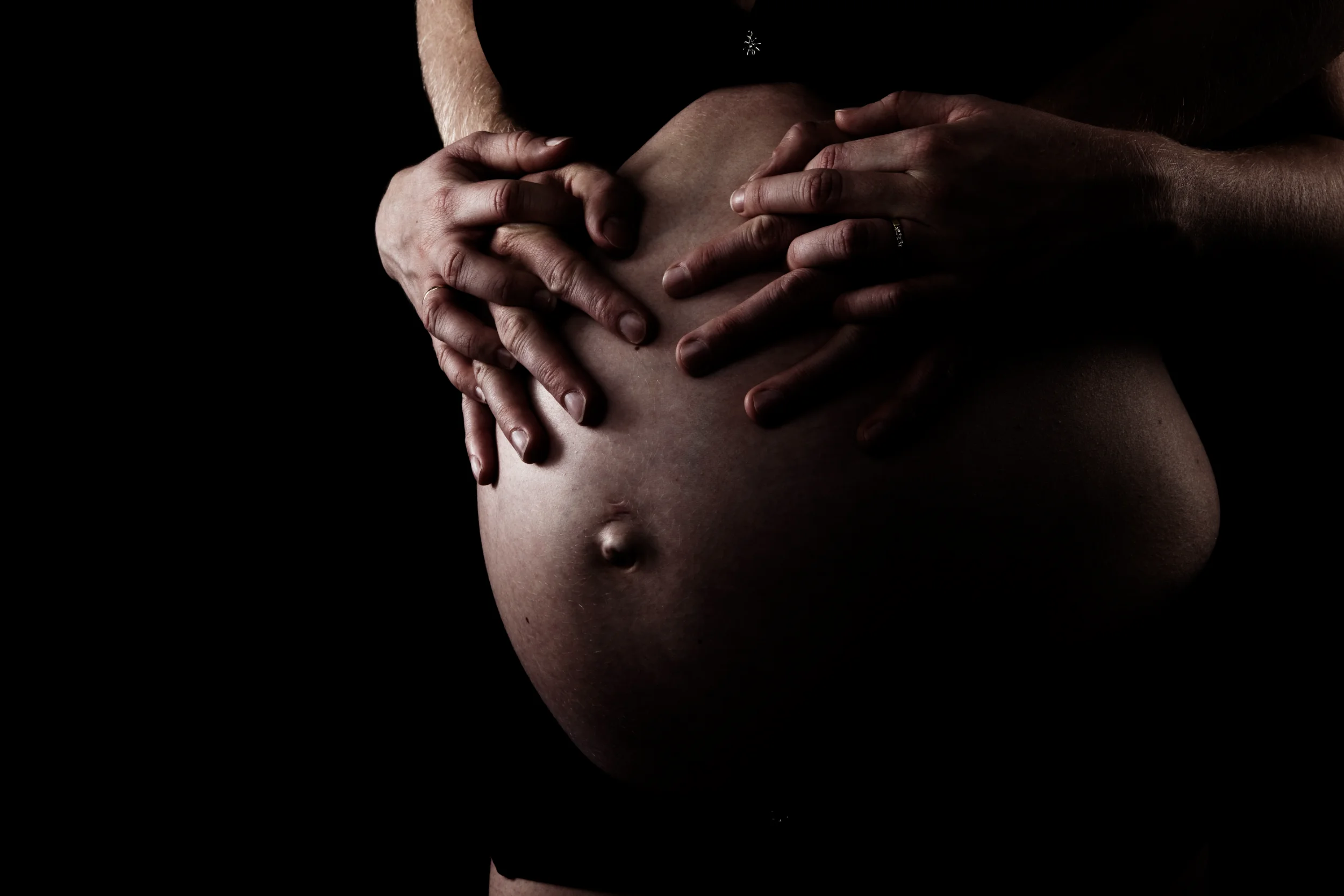 Nærbillede af gravid mave med hænder