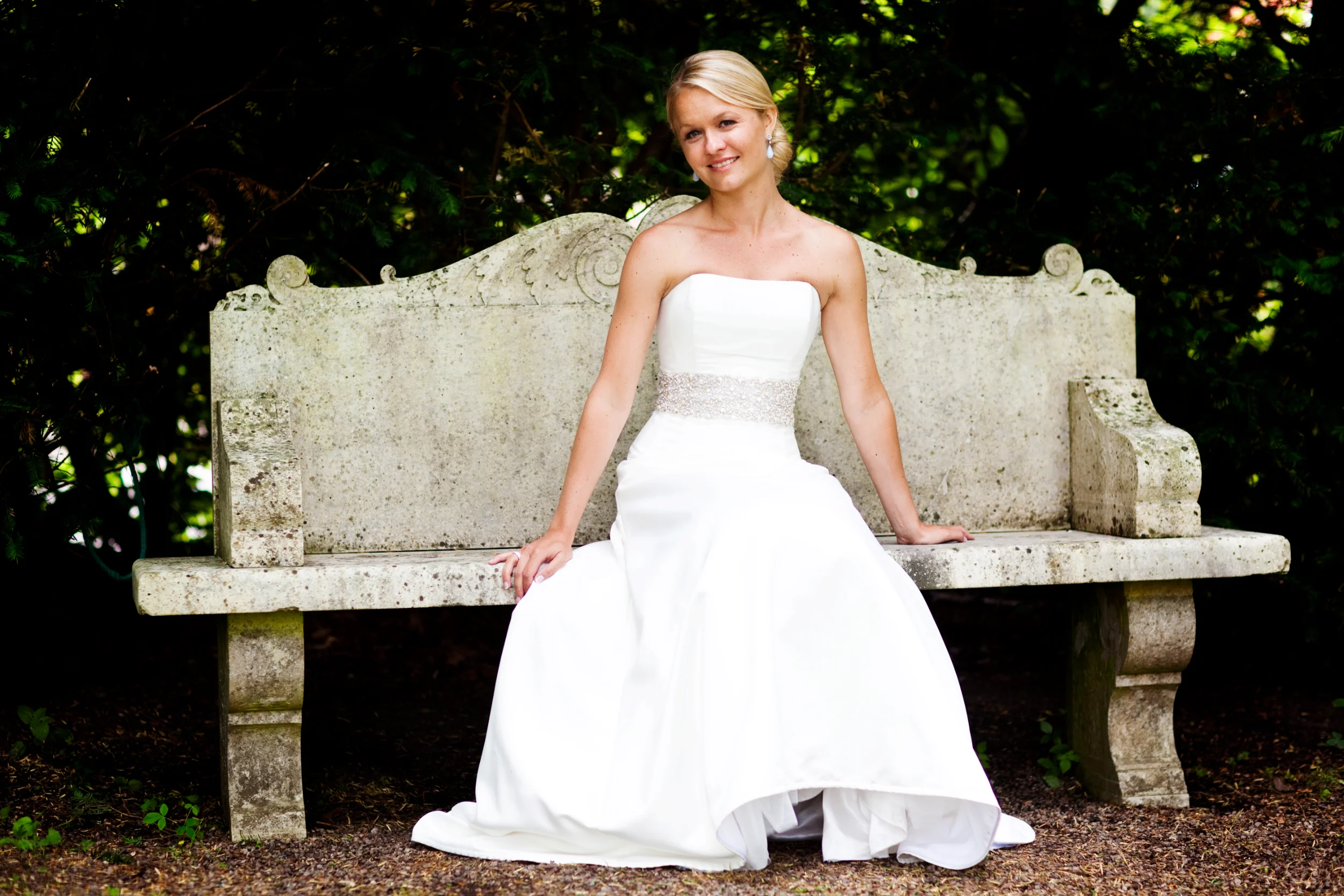 Bryllupsfotografering: Smilende brud på stenbænk i Virum
