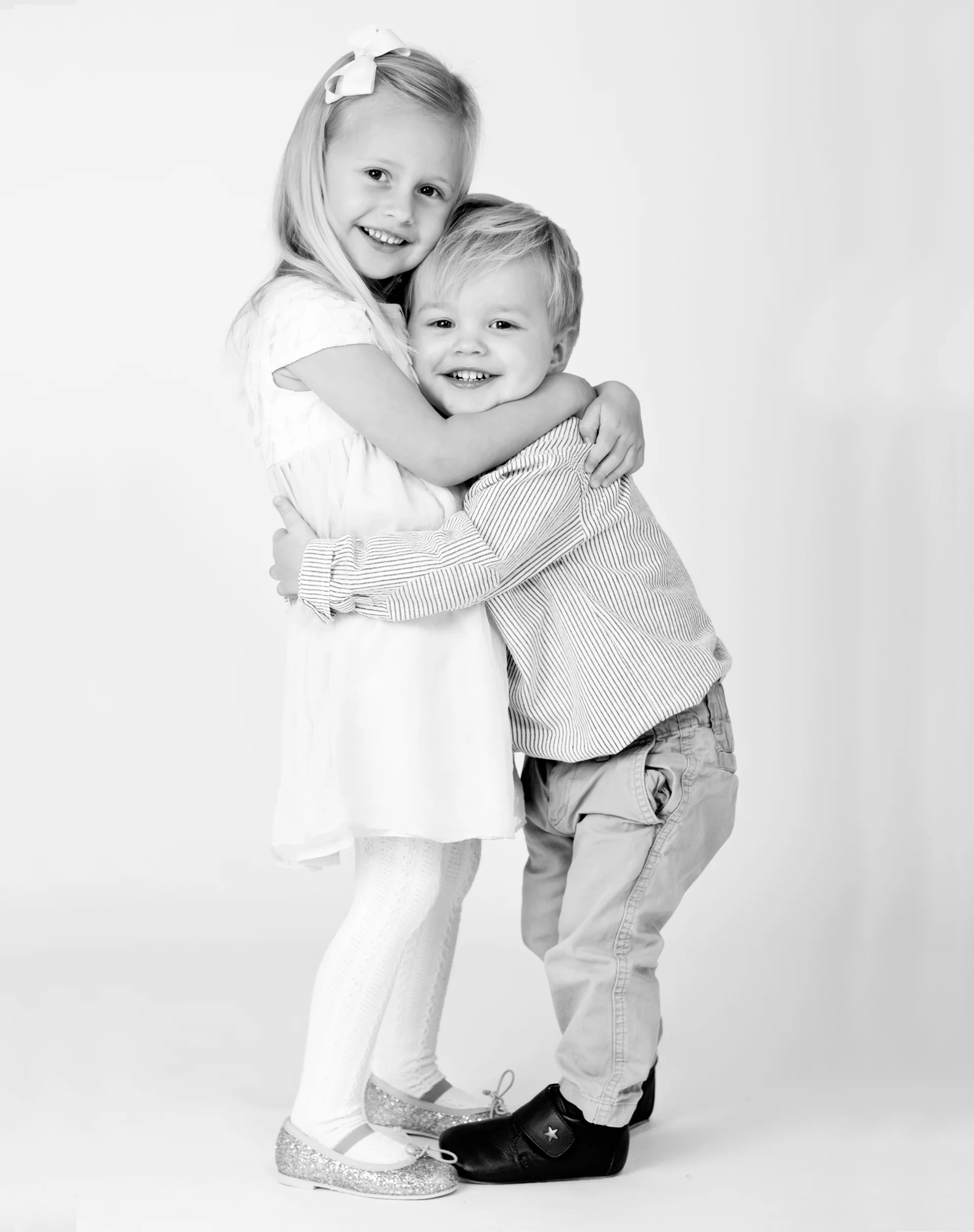 Søde søskende krammer i sort-hvidt børnefotografi