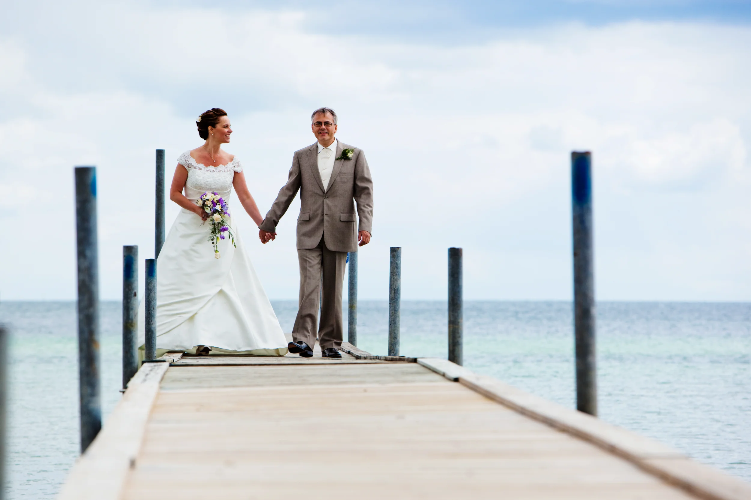 Bryllupspar hånd i hånd på badebroen
