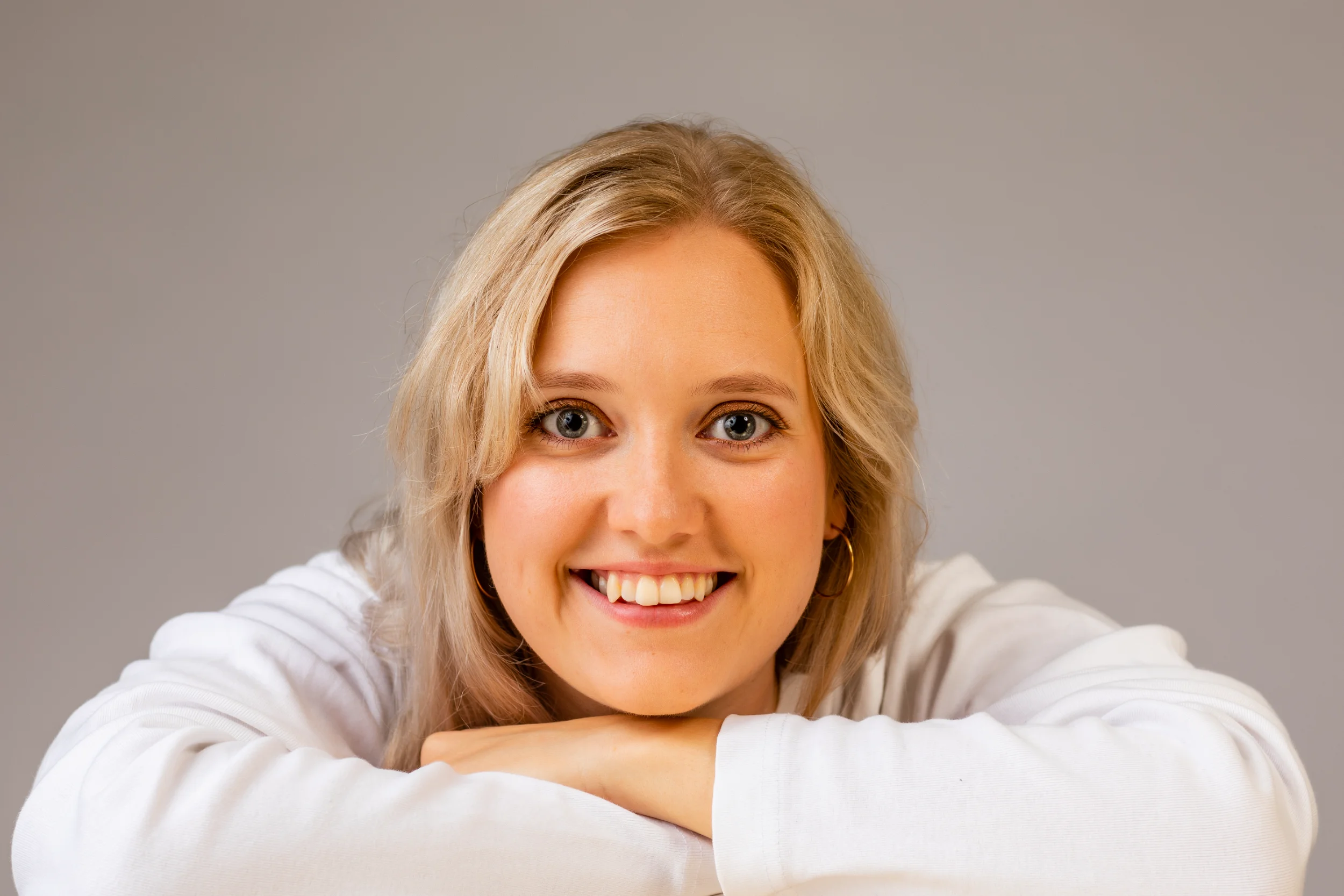 Nærbillede af ung smilende kvinde med blondt hår, der kigger direkte ind i kameraet, skaber et autentisk portræt.