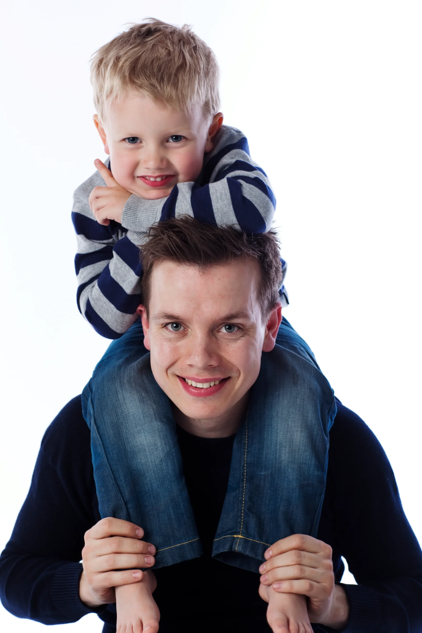 Børn: Far og glad smilende søn på skuldrene mod hvid baggrund i et lyst familiefoto. Virum portræt.