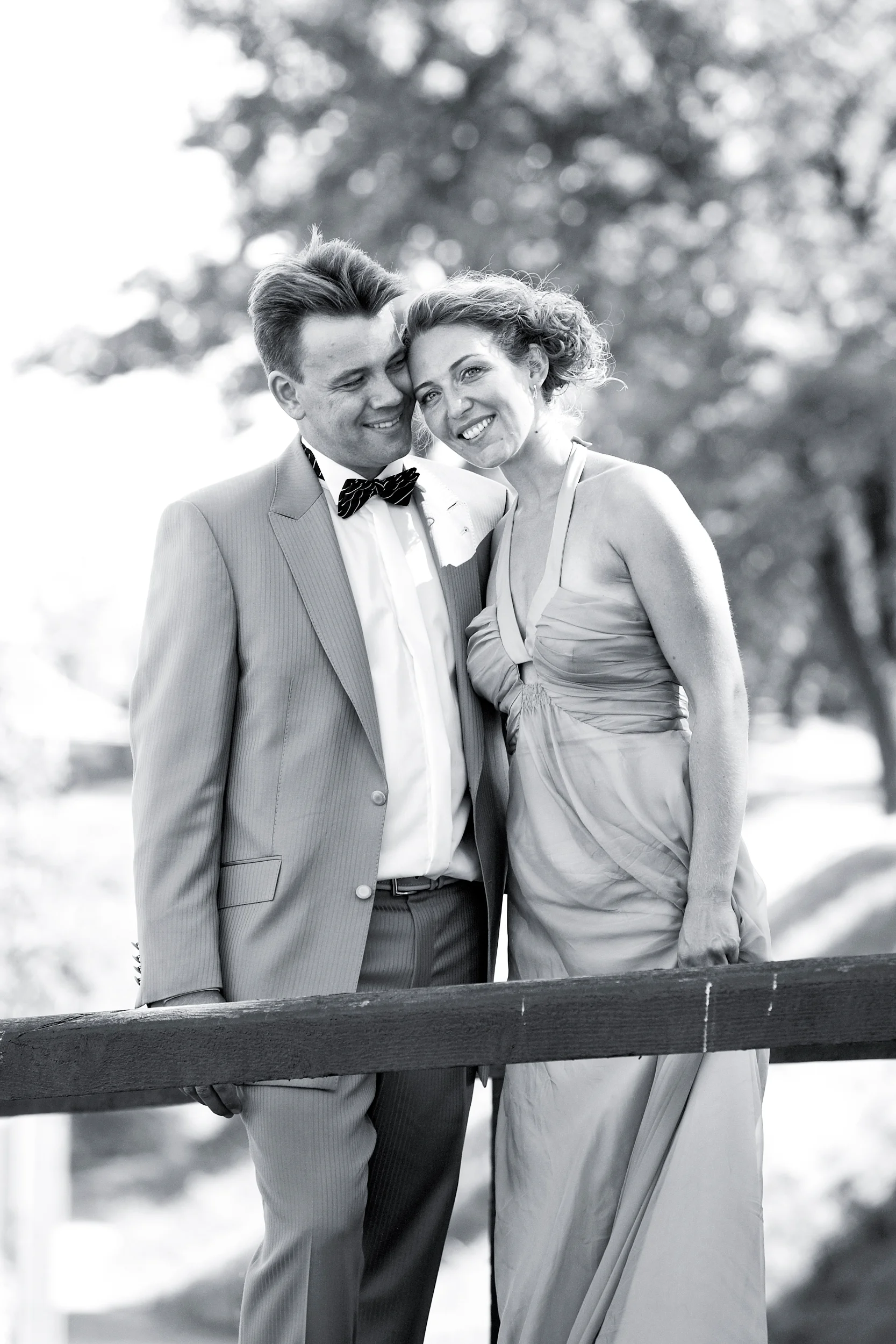 Sort/hvidt bryllupsfoto af smilende brudepar tæt sammen, med bruden der hviler hovedet mod gommens skulder.