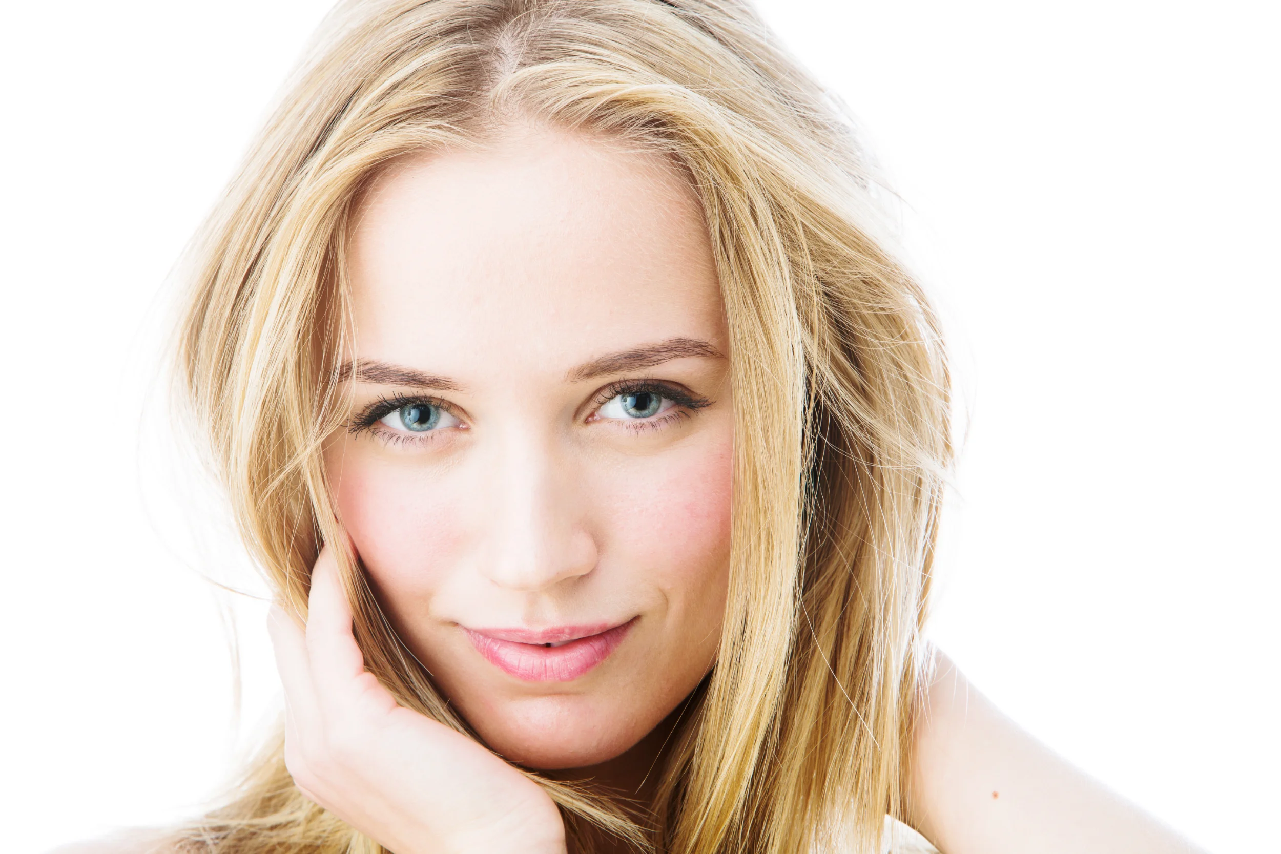 Nærbillede portrætfoto af en blond kvinde med klare blå øjne, smilende mod kameraet i blødt, lyst lys.