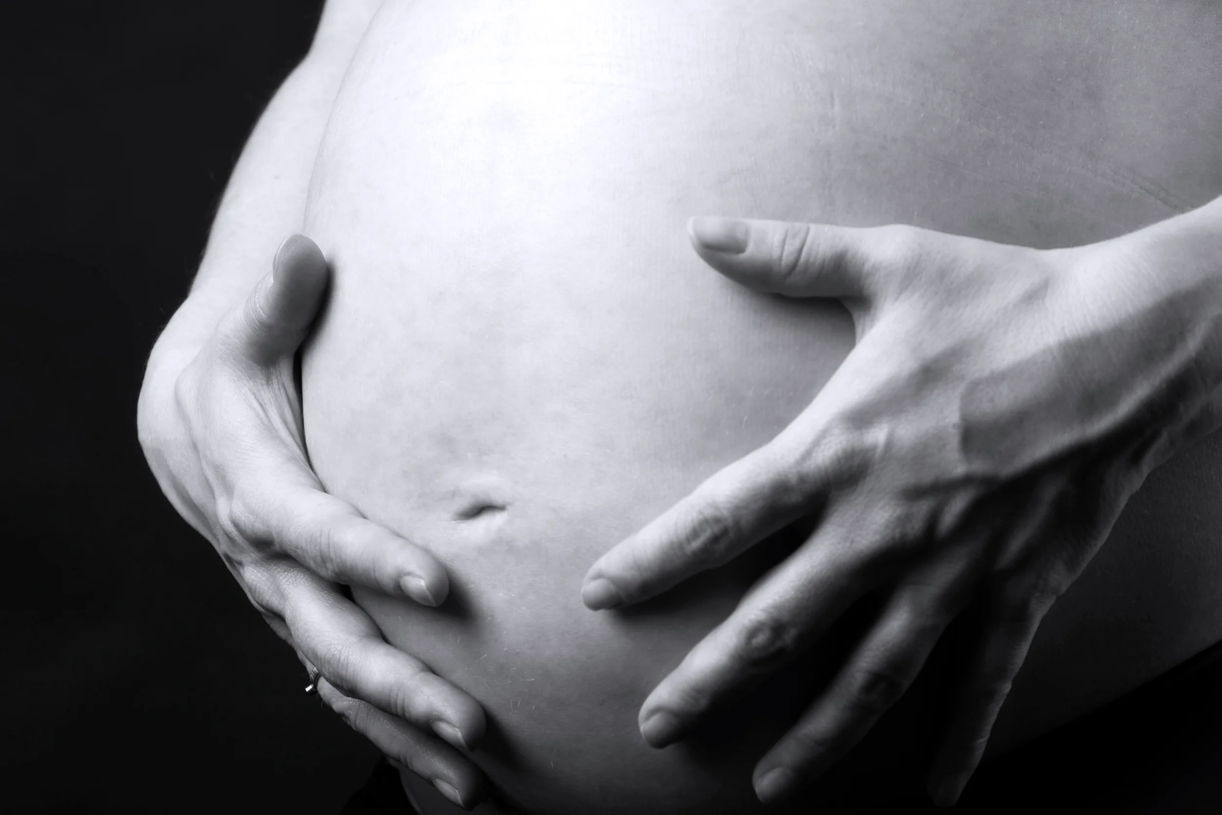 Nærbillede af gravid mave med hænder