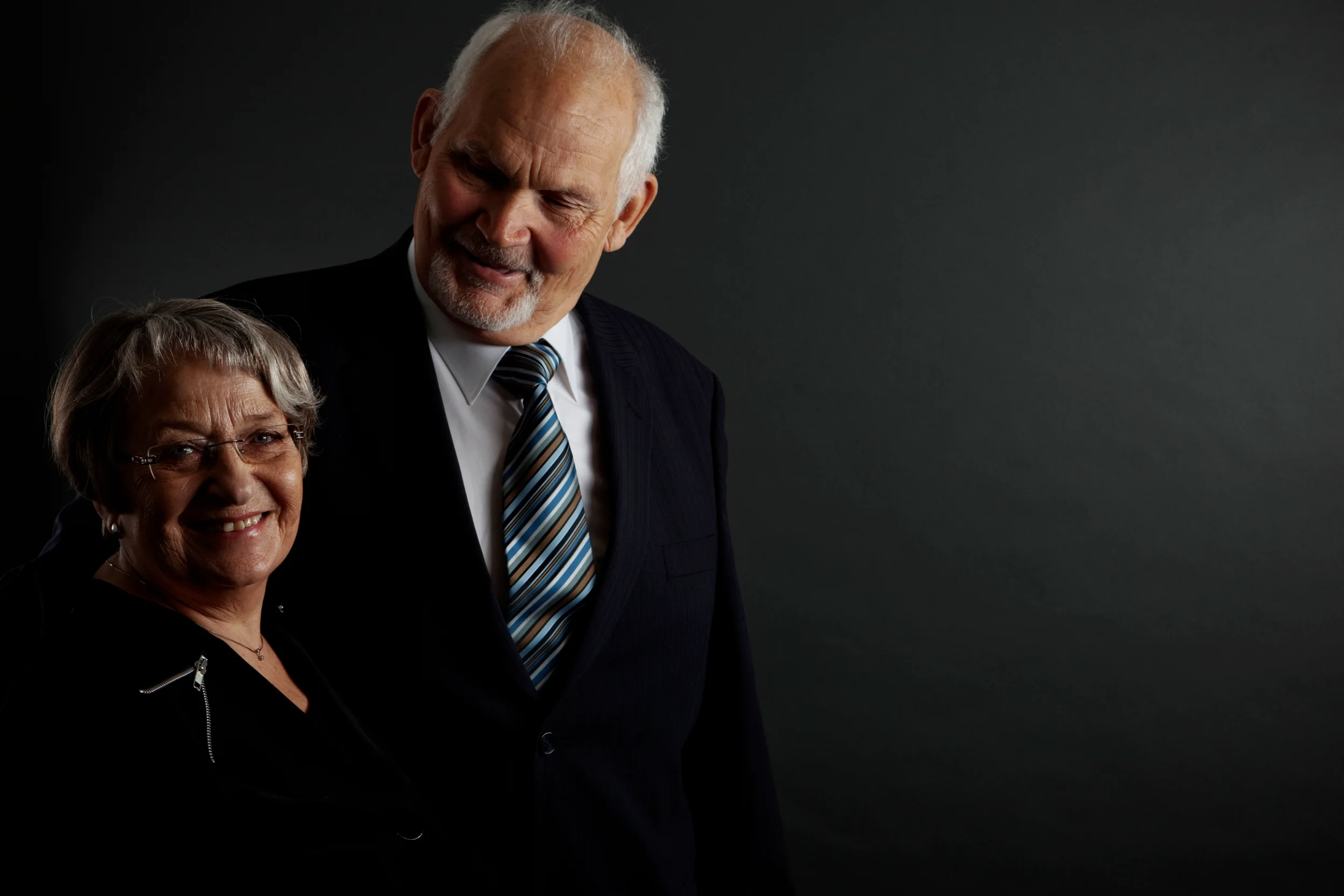 Professionelt sort/hvidt portrætbillede af smilende, ældre par hvor manden i jakkesæt kigger ned mod kvinden.