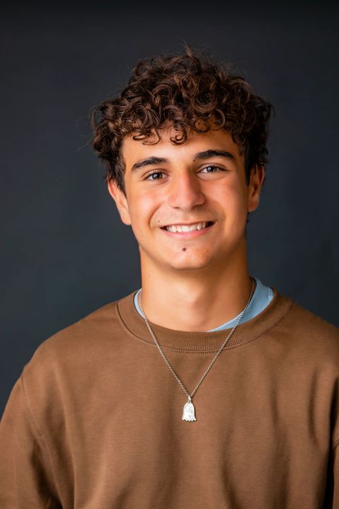 Ung mand med smil og naturlige krøller i portræt