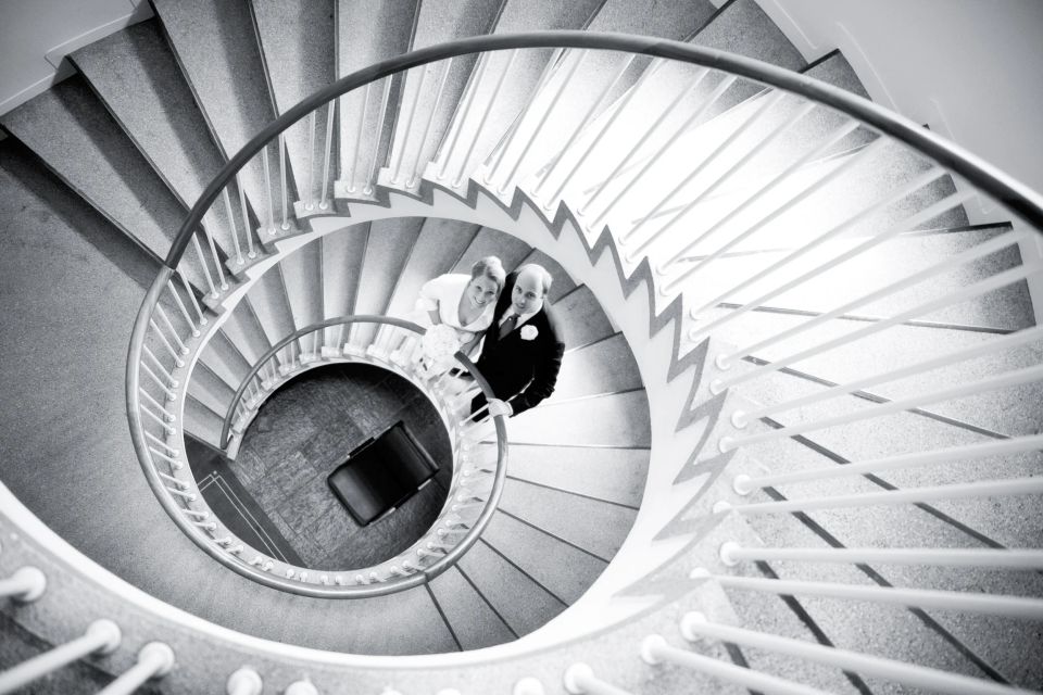 Bryllupsfoto: Sort/hvidt billede af nygift par set oppefra på elegant snoet trappe, der symboliserer deres vej sammen.