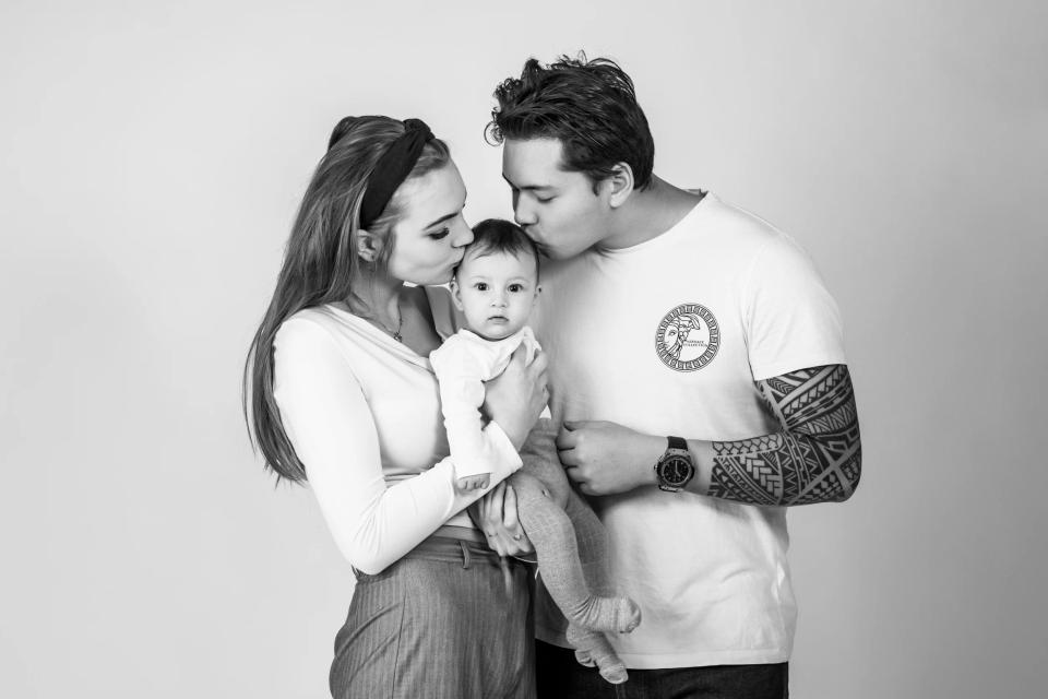 Sort-hvid babyfotografering: Forældre kysser nyfødt baby på panden. Et kærligt og autentisk babybillede.