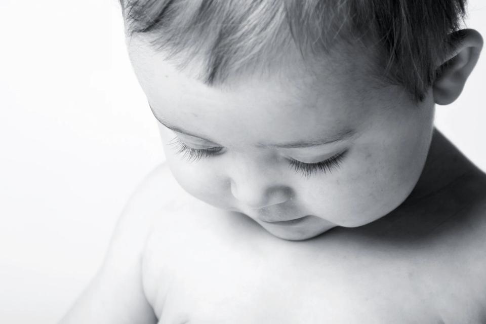 Nærbillede af baby, der sover fredfyldt, med lukkede øjne og bløde træk. Babyfotografering i sort/hvid