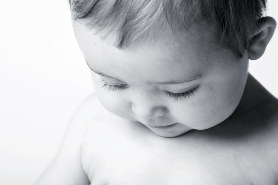 Nærbillede af baby, der sover fredfyldt, med lukkede øjne og bløde træk. Babyfotografering i sort/hvid