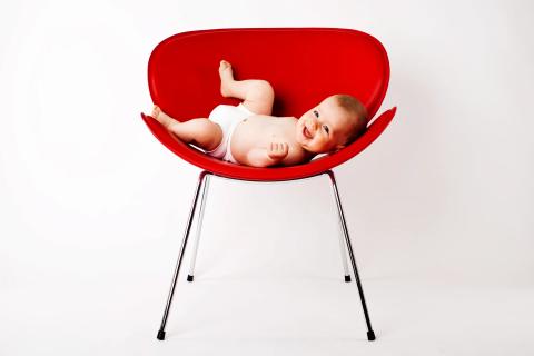 Legesyg baby med glæde i rød stol