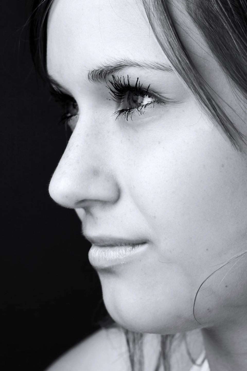 Sort/hvid portrætfoto af kvindes ansigt i profil, med fokus på kindben og de lange øjenvipper i blødt sidelys