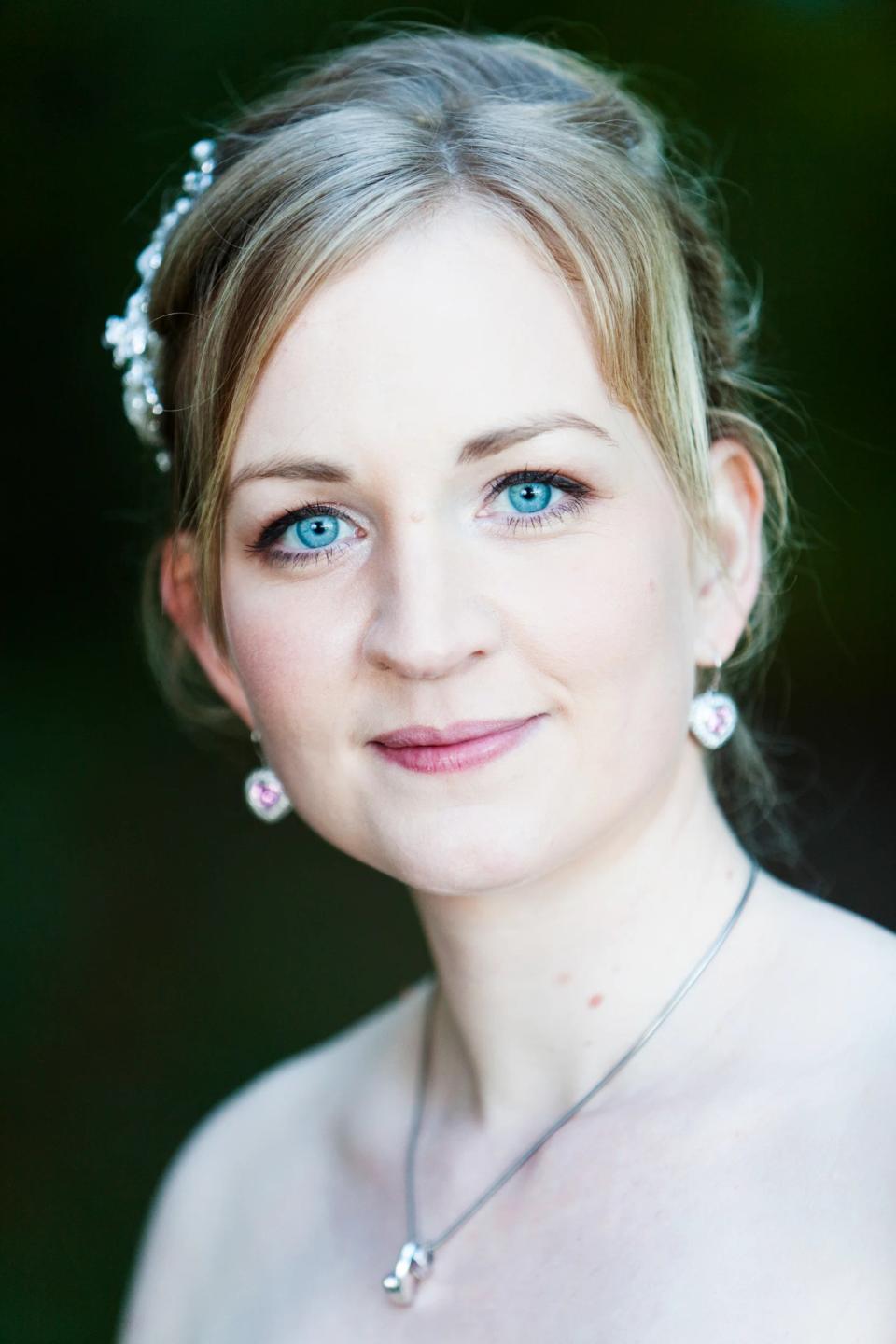 Nærbillede af brud med klare blå øjne, perlehårpynt og smil, et autentisk bryllupsfoto