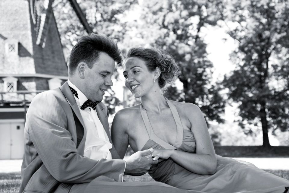 Bryllupsfotografering: Brudepar slapper af i græsset ved Kastellet med møllen i baggrunden i sort/hvid