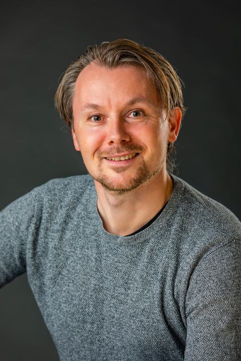 Studieportræt af mand med varmt smil og skæg