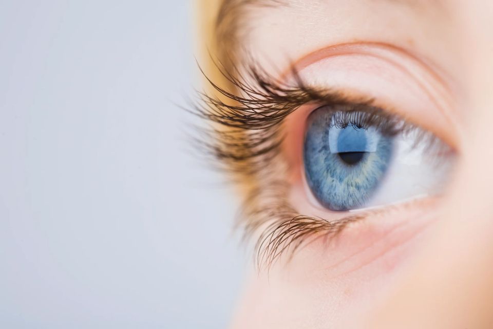 Nærbillede af et blåt børneøje med lange vipper, der kigger mod højre i et lyst portrætfoto.
