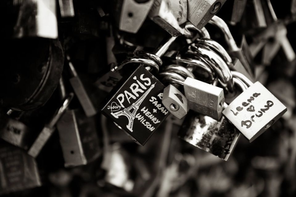 Nærbillede af mange "kærlighedslåse" i sort-hvid. Fokus på en lås med Eiffeltårnet og teksten "Paris".