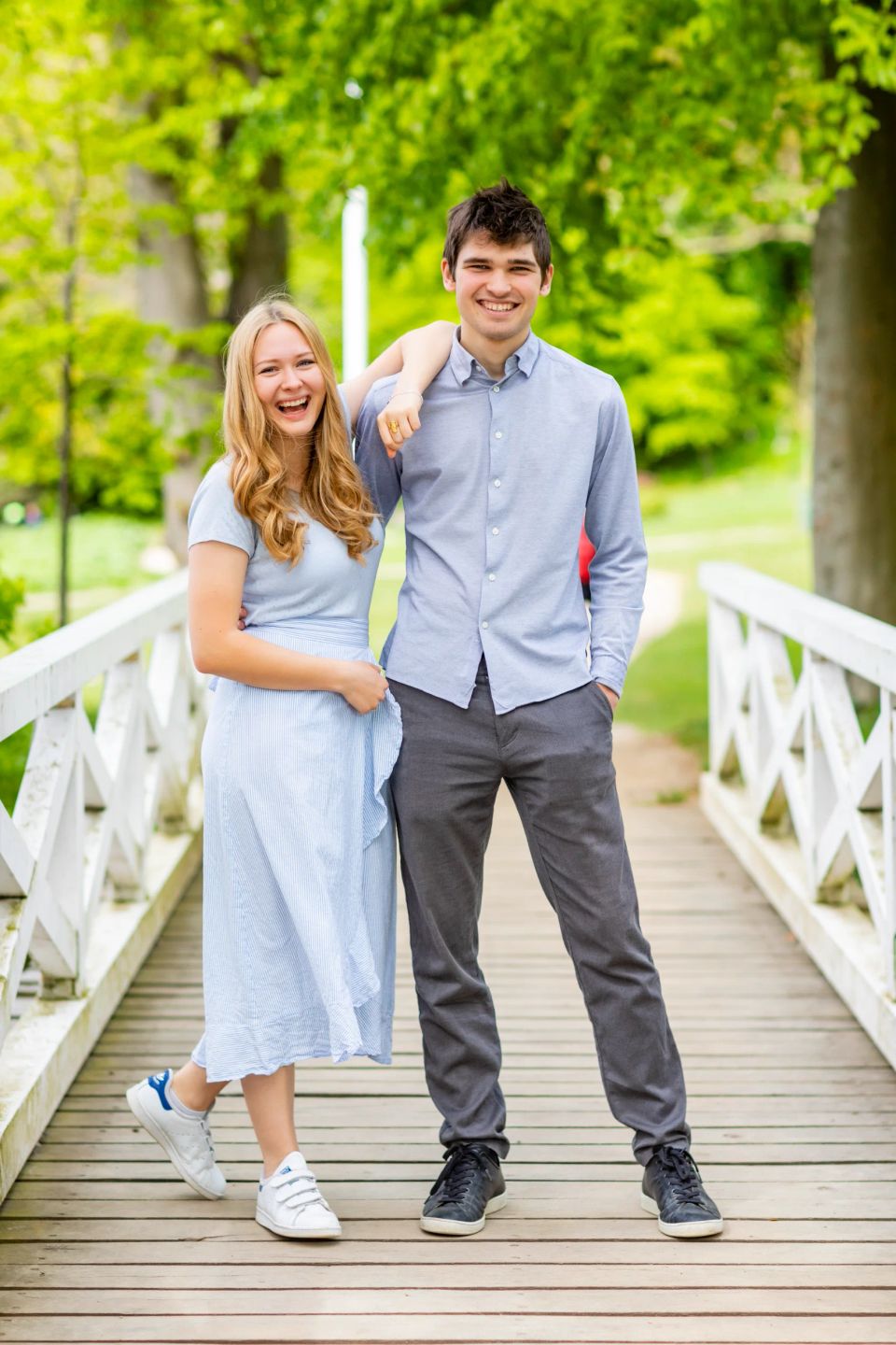 Glad ung familie poserer på hvid bro i Virum med smil og sommerligt tøj i blødt dagslys.