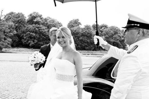 Ankommende brud med parasol og gommen i baggrunden