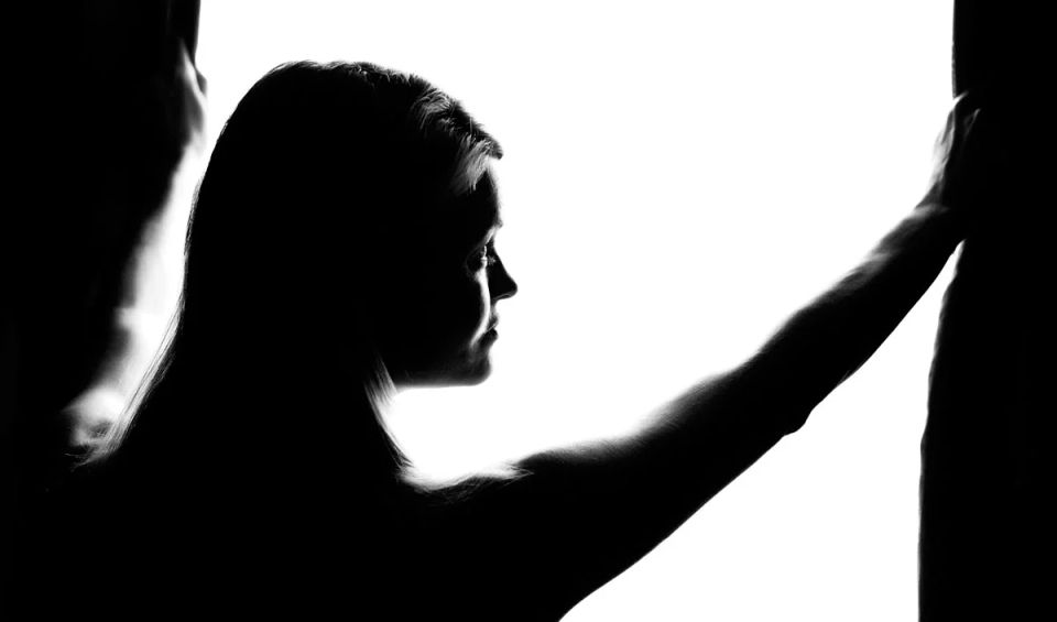 Sort-hvid portrætfotografi af en kvinde i silhuet, der kigger mod venstre i blødt, diffust lys. Hendes ansigt er delvist o...