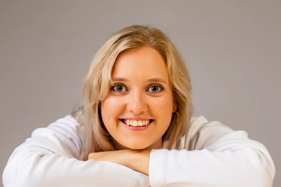 Nærbillede af ung smilende kvinde med blondt hår, der kigger direkte ind i kameraet, skaber et autentisk portræt.