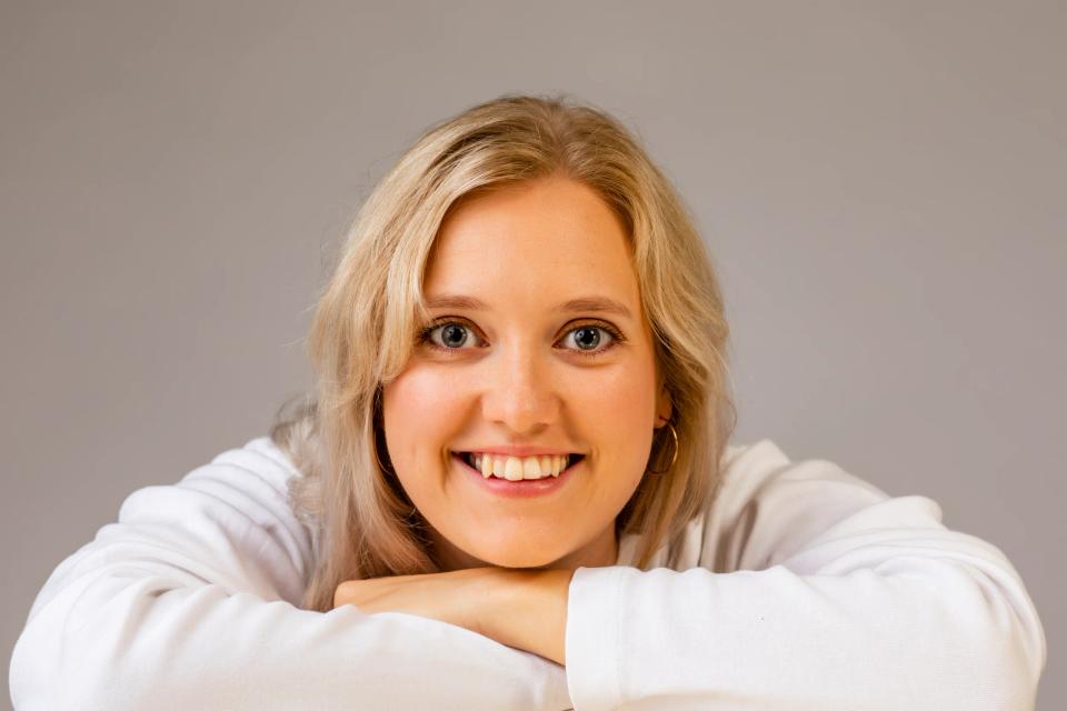 Nærbillede af ung smilende kvinde med blondt hår, der kigger direkte ind i kameraet, skaber et autentisk portræt.
