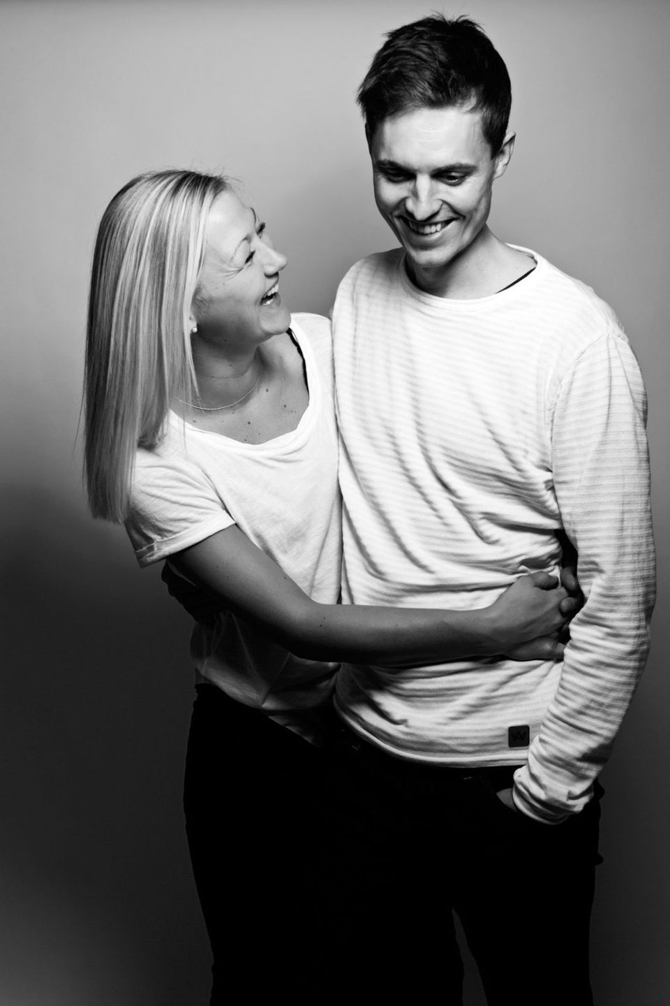 Sort/hvid portrætfoto af smilende, forelsket par der kigger på hinanden med blødt lys og intim stemning.