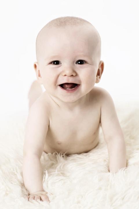 Glad baby med strålende smil i et ægte portrætbillede
