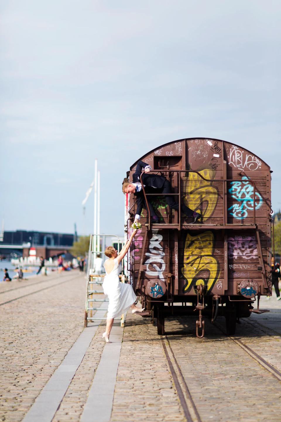 Brudepar på graffitivogn. Brudgom giver brud blomster fra toppen. Legesyg bryllupsfotografering i dagslys.