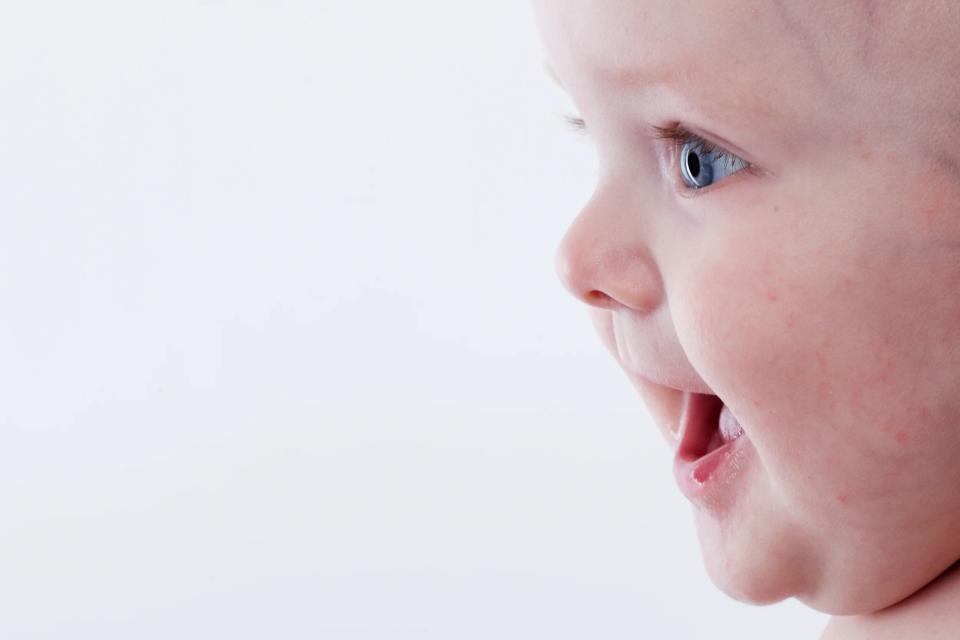 Nærbillede af nysgerrig baby i sort/hvid, der ser opmærksomt mod højre med åben mund. Et charmerende babyfotografi.