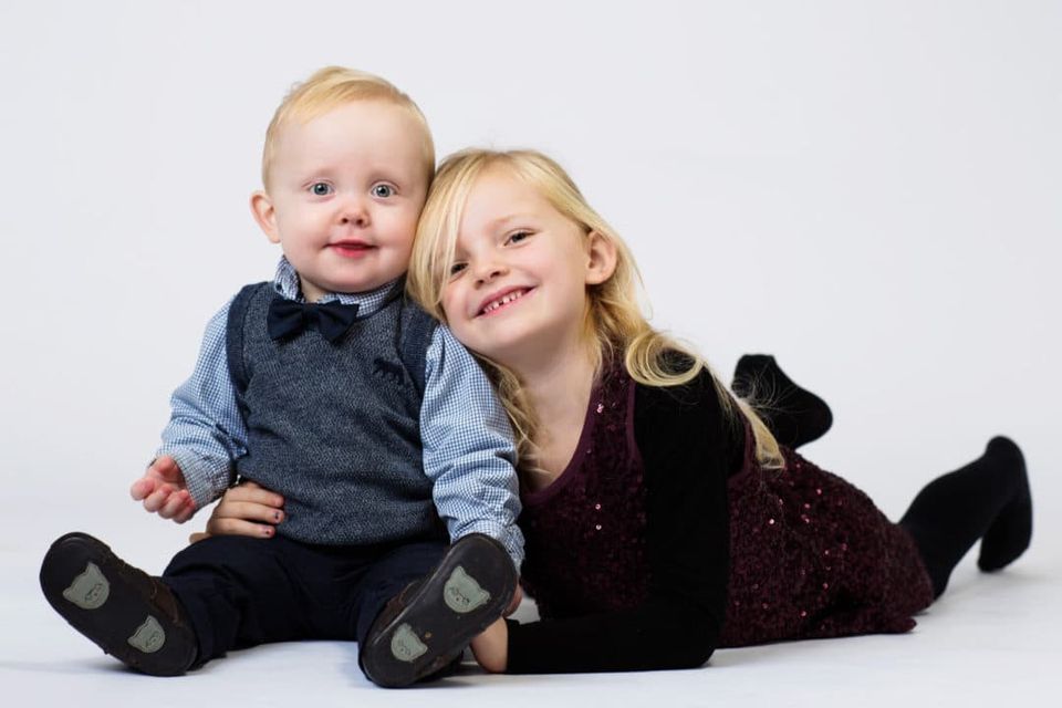 Børn: Søskendepar med en smilende pige, der ligger ved siden af sin lillebror med et stort, charmerende smil.